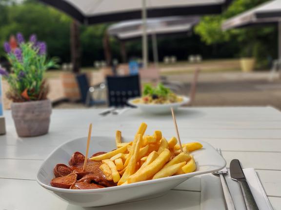 Currywurst mit Pommes auf der Außenterrasse des Bad Bistros