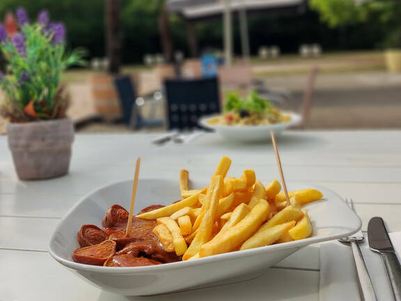 Currywurst mit Pommes auf der Außenterrasse des Bad Bistros