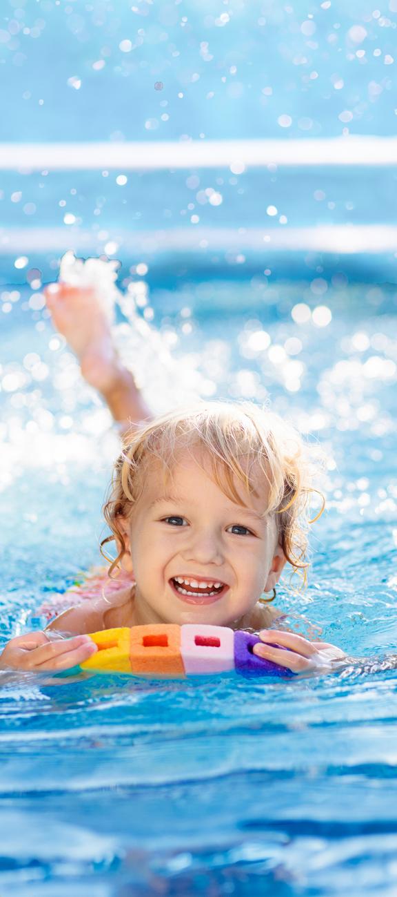 Kind im Schwimmbecken mit buntem Schwimmbrett, das beim Schwimmenlernen hilft.